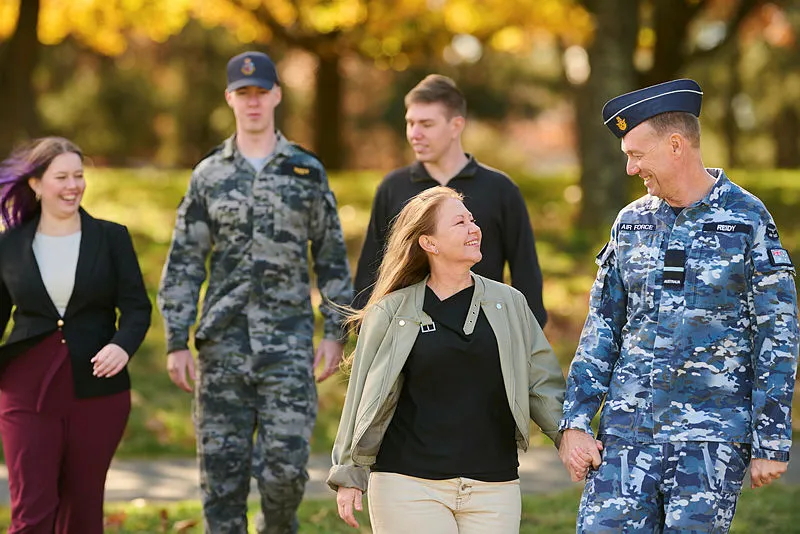 A RAAF member and a Navy member in a park, accompanied by family members
