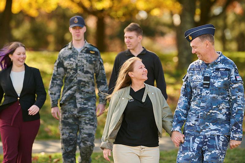 A RAAF member and a Navy member in a park, accompanied by family members