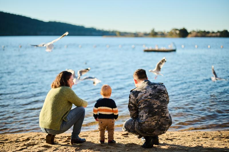 An Australian Navy member and his family look out at the water and seagulls