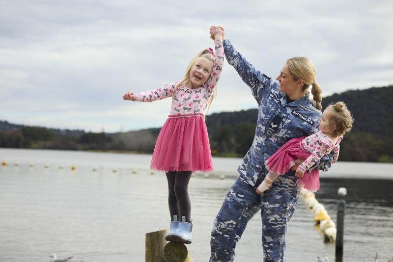 An Australian Air Force member and her children play next to the water 