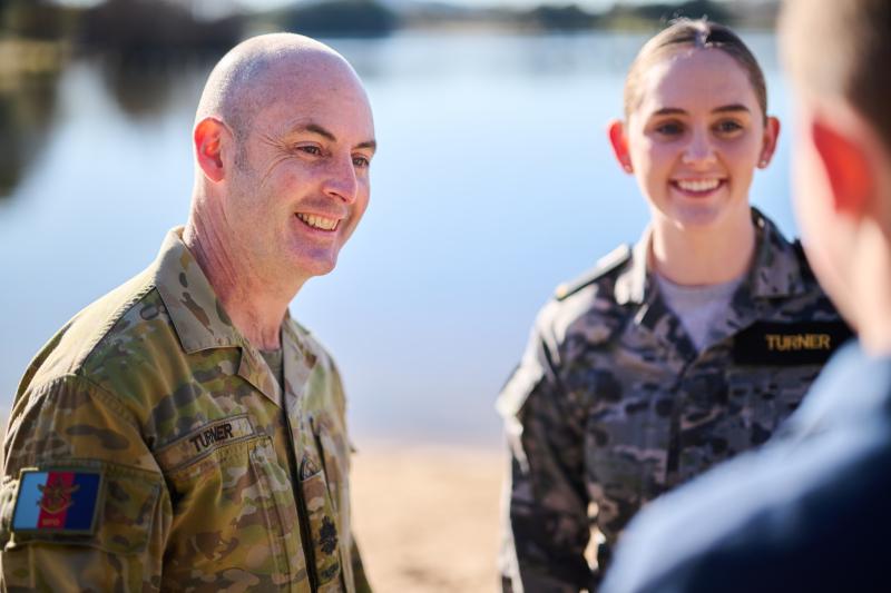 Three ADF members standing beside a lake talking and smiling together